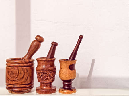 Three mortars with pestles of different sizes against the background of a light wallの写真素材