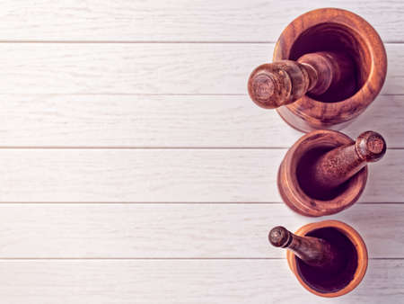 Three mortars with pestles of different sizes on a background of light boards. View from aboveの写真素材