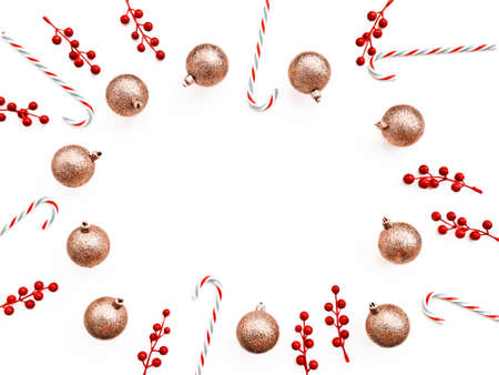 Christmas decorations (golden balls, candy, twigs with red berries) are placed in a circle on a white background. There is a blank space for textの写真素材