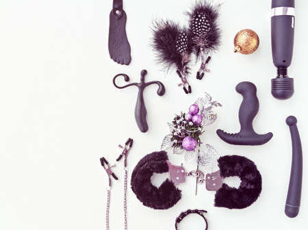 Various sex toys (hancuffs, vibrator, nipple clamps and other) and Christmas decorations on a light...