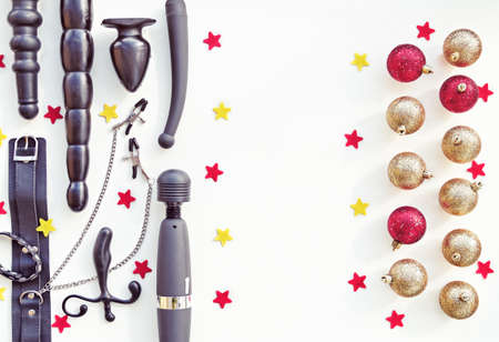 Various sex toys and Christmas decorations on a light background with red and yellow stars. Image for the festive season, for sales and discounts in sex shops. There is a free space for textの写真素材