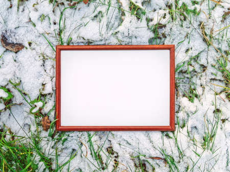 The wooden frame is on a snow-covered grass. Autumn or winter backgroundの写真素材