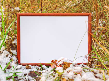 The wooden frame is on a snow-covered grass. Autumn or winter backgroundの写真素材