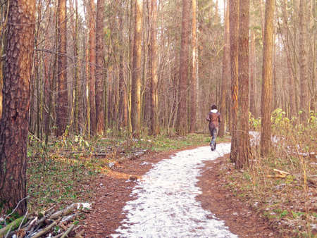 The girl runs along the snow trail in the autumn forest. Image on the topic of maintaining the body...