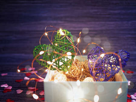 Two wicker hearts together with a luminous garland. Around are scattered small hearts of cloth. Beautiful and romantic backgroundの写真素材