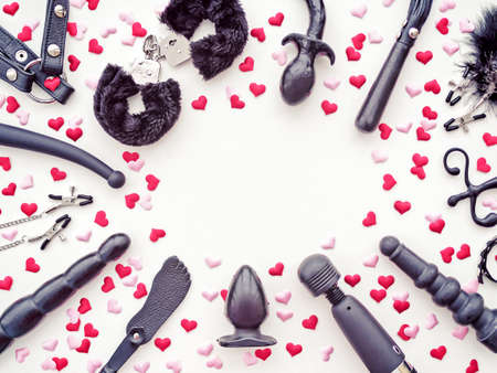 Various sex toys are arranged on a white background with pink and red hearts. Romantic background for goods from a sex shop or Valentine's Dayの写真素材