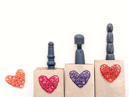Various sex toys (dildos and wand-massager) are in paper bags. On top of them are figures of wicker hearts. The idea to buy gifts for Valentine's Day.の写真素材
