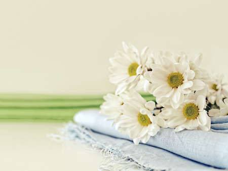 A bouquet of fresh white chamomile chrysanthemums is on a folded blue linen cloth (napkin or...