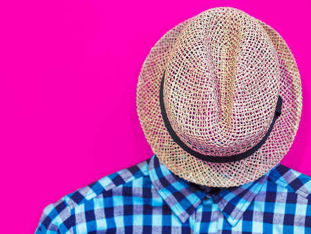 A straw hat and a blue men's shirt made from organic cotton are on a purple background. Image for advertising clothing store, discounts, fashion blogの写真素材