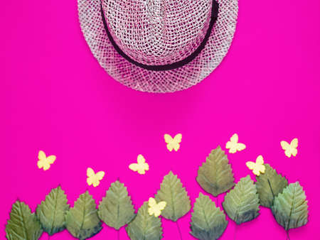 A hat knitted from straw, green leaves and yellow butterflies are on a purple background. Image for spring-summer advertising store accessories, sales and salesの写真素材