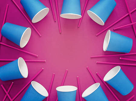 Blue empty paper cups are arranged in a circle on a purple background. Straws are scattered around. Image for celebration, party. Artificial increase in color and noise.の写真素材