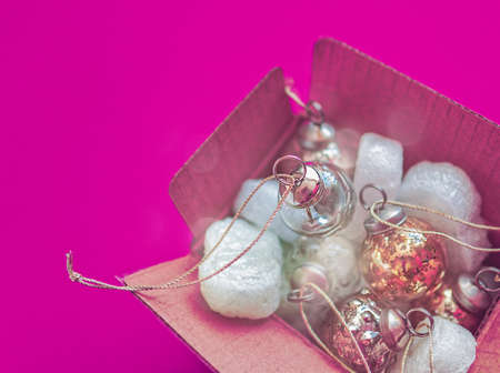 Christmas decorations are among the foam in an old cardboard box on a purple background. Waiting for the beginning of the holiday or vice versa its endの写真素材