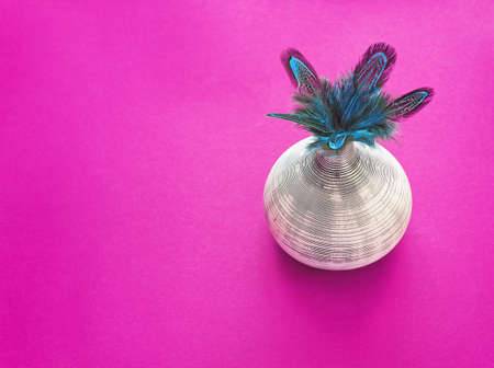 A bouquet of blue-colored pheasant feathers is in a ceramic vase with strips. Purple background. Home decor. There is a place for text. Image for blog or magazineの写真素材