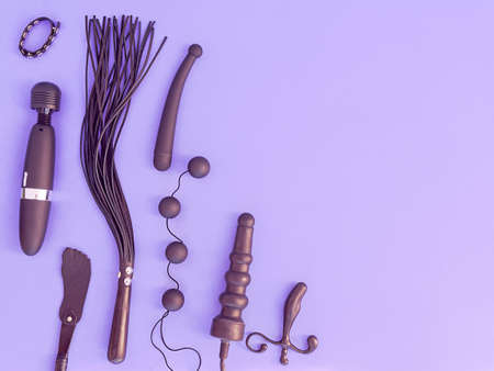 Various sex toys (leather whip, dildo, vibrator, love balls and other) are on a purple background. The image is suitable for advertising a sex shop or for displaying diversity in sexual pleasuresの写真素材