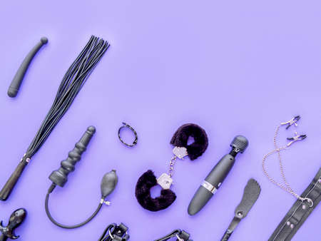 Various sex toys (fur hancuffs, vibrator, leather whip, dildo, spanking paddle and other) are on a violet background. Image for sex shop advertisingの写真素材