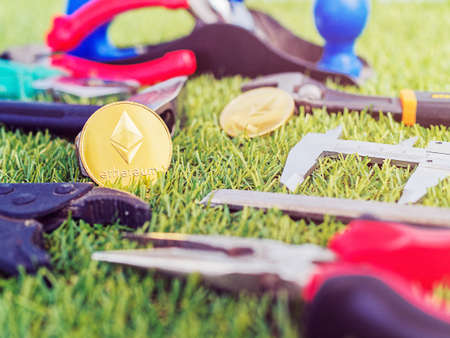 Coins of crypto currency Ethereum and various instruments of the real world are on the green grass. Image on the topic of earningsの写真素材