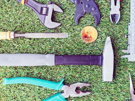 The Crypto currency coin Ethereum is located along with tools from the real world on green grass. Image on the theme of the hard work in the real and digital worldの写真素材