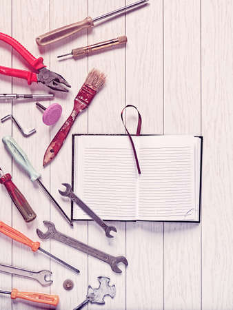 Open diary with empty pages and various tools are on a white wooden background. An image of the planning of working hours, setting goals. Image is suitable as a greeting on Labor Day or Father's Dayの写真素材