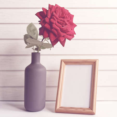The red rose is in a high gray bottle. It's a wooden frame with an empty space for text. White wooden backgroundの写真素材