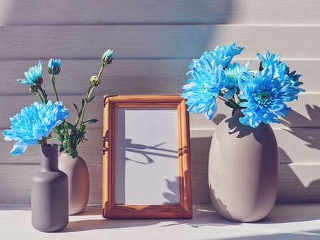 An empty wooden frame. They are the vases with blue chrysanthemums in them. On the petals of flowers.の写真素材