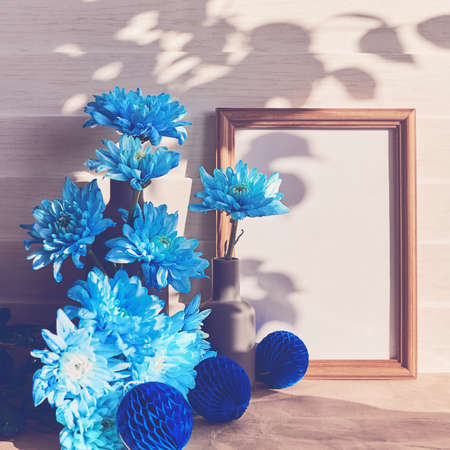 A bouquet of blue chrysanthemums or chamomiles and decorative paper balls are on a white wooden...