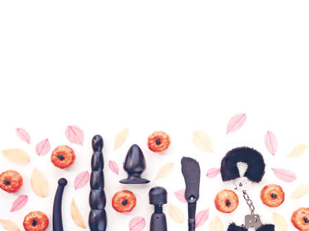 Various sex toys (vibrator, dildo, anal plug, spanking pad, handcuffs), autumn fallen leaves and artificial pumpkins are on a white background. The image is suitable for advertising.の写真素材