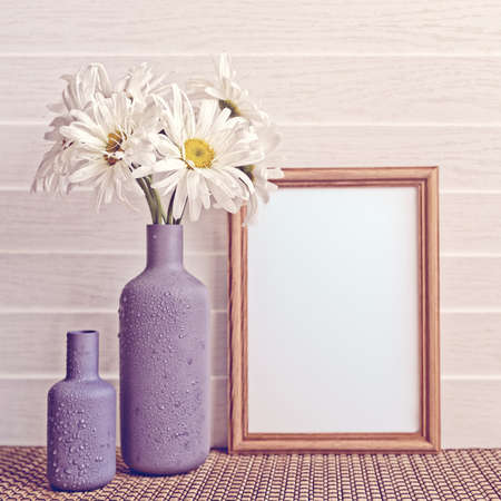 White chamomiles are in a gray vase. The vase is covered with drops of water. There is an empty...