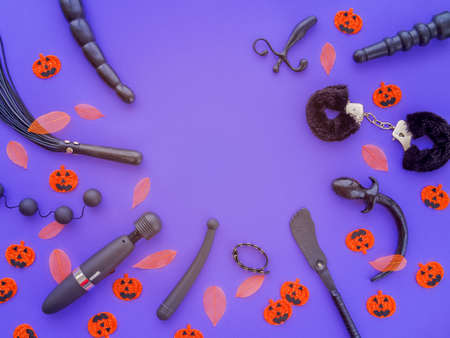 Various adult toys along with fallen leaves and pumpkins with funny faces are located on a purple background.の写真素材