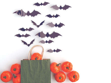 Little pumpkins and bat figures isolated on white background. The bed is a green paper bag with handles for purchases. Image for store advertising to Halloween.の写真素材