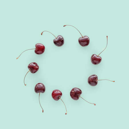 Ripe cherries are on a green pastel color. Flat lay, top view minimal composition.
