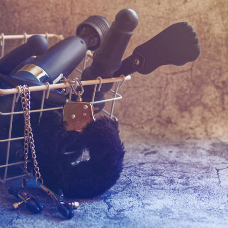 Various sex toys are in a wicker metal basket on a gray stone background. Idea for sex shop advertisingの写真素材