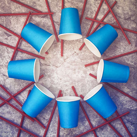 Blue empty paper cups are arranged in a circle on a stone background. Straws are scattered around. Image for celebration, party. Flat lay, top view minimal composition.の写真素材