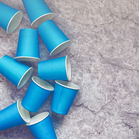 Blue paper disposable cups are on a stone background. Waiting for the festival, parties, events....