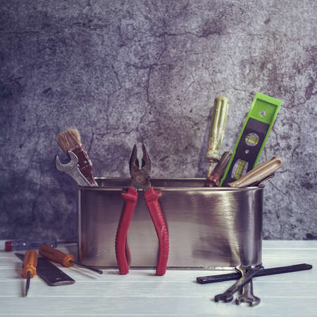 Various tools (screwdrivers, brush, wrench and others) are located in a metal box with rounded...