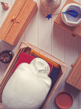 The decorative figure in the form of a human skull is on top of the books in a wooden box. Nearby...