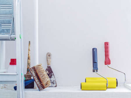 Internal repair of the room. Preparation for paint work. Various brushes, rollers and scraper are near the white wall.の写真素材
