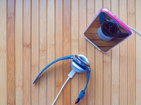 Wireless charging of wearable (mobile) devices. A red smartphone in a transparent case and a smart watch with a blue silicone strap are in cradles on a wooden background.の写真素材