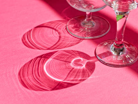 Glass goblets are on thick colored paper. The rays of light refract through the glass and create bizarre shadows.の写真素材