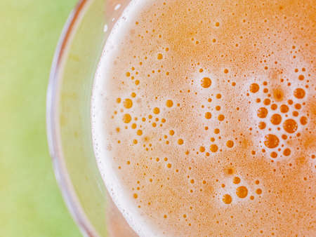 Foam head on the surface of a beer in a glass goblet. Top view. Green background.の写真素材