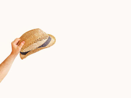 A man's hand holds a summer straw hat. The concept of outdoor recreation, vacation. Copy space.の写真素材