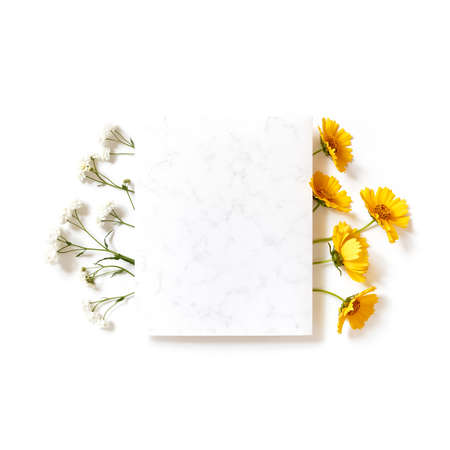 Flower composition. A template from a sheet of paper with a marble pattern is on a white background. Nearby are yellow flowers. Social media background. Holiday layout. Flat lay, copy space.の写真素材