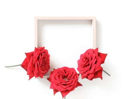 Minimalistic flower arrangement. Mock up of empty wooden photo frames and red roses. White background. Flat lay. Top view. Copy space.の写真素材