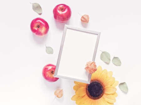 Autumn composition. Template made from empty metal photo frame, dried leaves, flowers and ripe red apples. Top view. Copy space.の写真素材