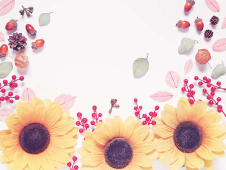 Autumn composition. A frame made of acorns, leaves, red berries, cones and a flower is on a white...