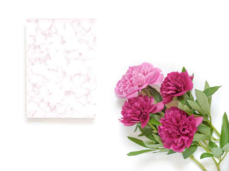 Flower composition. A bouquet of red and pink peonies and a piece of paper with a marble pattern are on a white background. Flat lay. Copy space.の写真素材