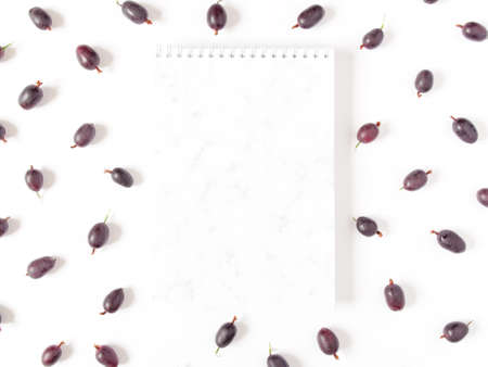 Autumn berry composition. A blank notebook with a marble pattern and berries are on a white...