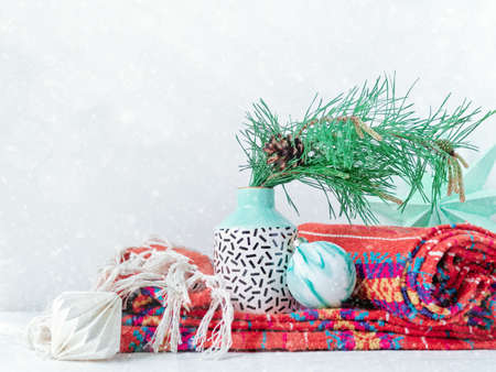 Christmas composition. A vase with a natural pine branch is in a vase on a knitted blanket. There...