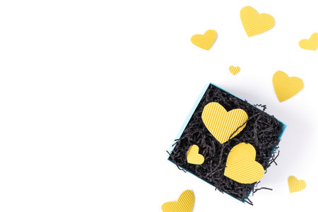 The yellow heart-shaped shapes are cut from cardboard and are on black paper in a gift box. Minimalistic concept for valentine's day, mother's day. Flat lay. Top view.の写真素材