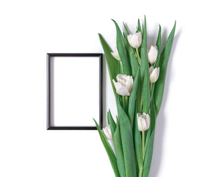 A bouquet of white tulips and a black blank photo frame are on a white background. Floral template...