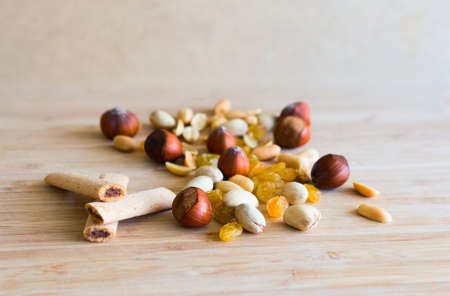 Peanut, hazelnut, pistachio, raisin, jam sticks  on a light wooden cutting board  Selective focusの写真素材